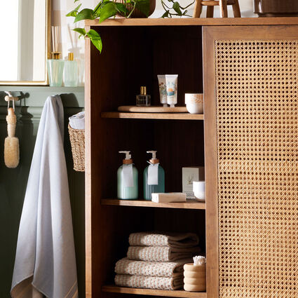 Cane and wood storage armoire in bathroom