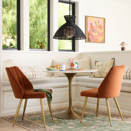 A dining nook featuring a round table and minimalist dining chairs