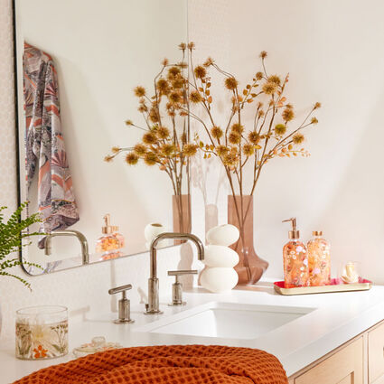 Bathroom counter with flower stems in clear colored glass vases
